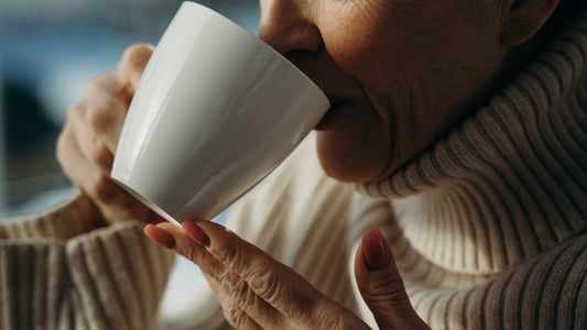 Older woman drinking coffee from a white mug 